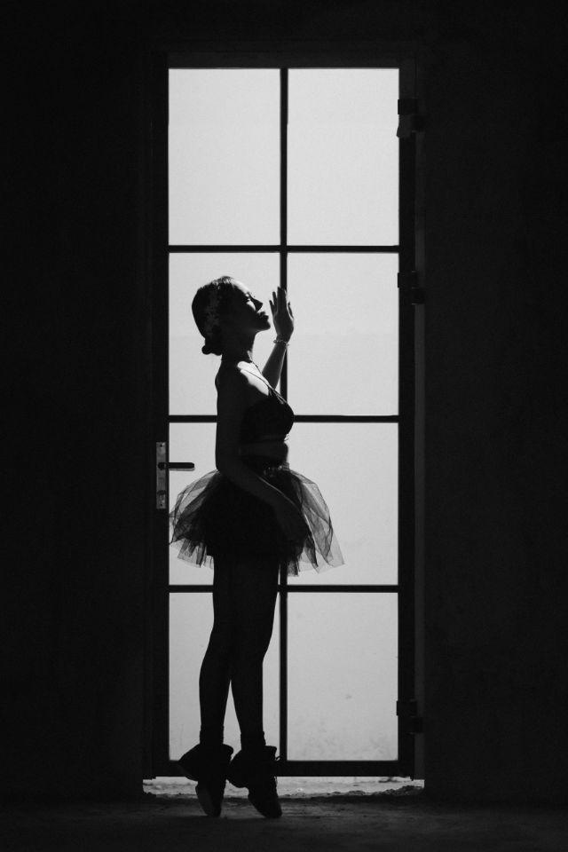 Mulher dançando em frente a uma janela